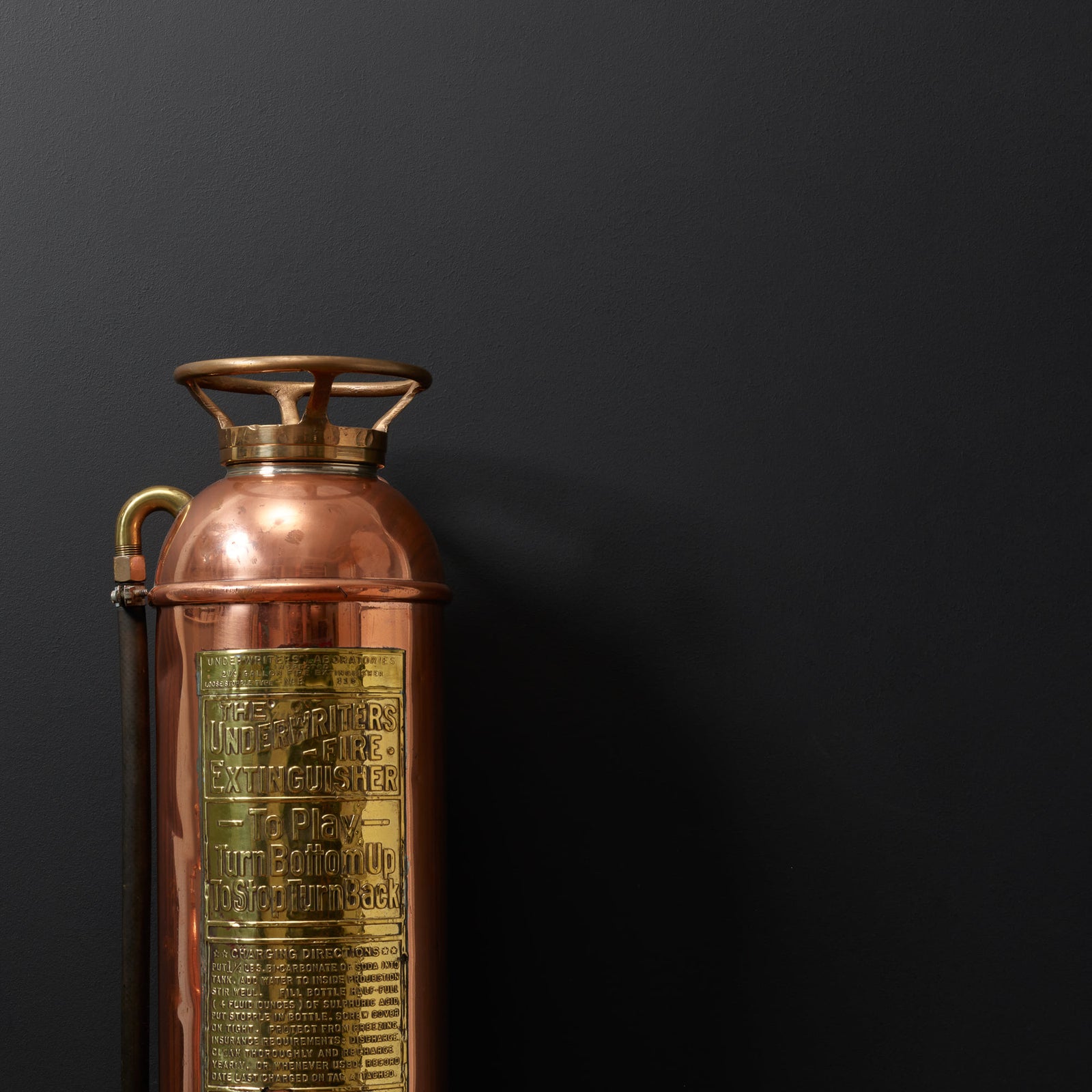 Mustaa seinää vasten kuparinen vintagekoriste. 