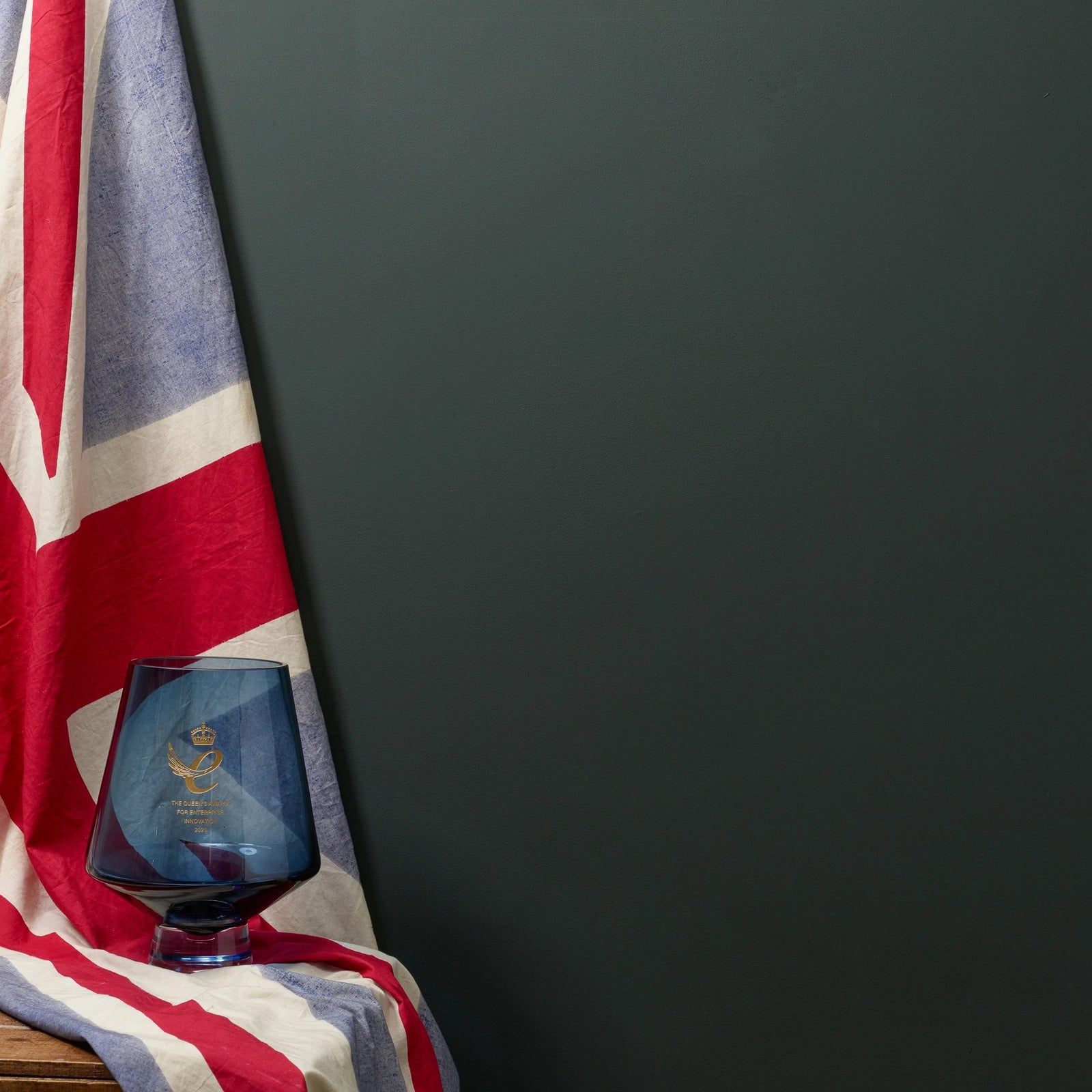Tummanvihreää seinää vasten brittien lippu ja lasinen Frenchic sajan Queens Award palkintomalja. 